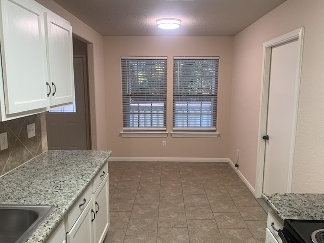 unfurnished dining area featuring a textured ceiling, tile patterned flooring, and baseboards