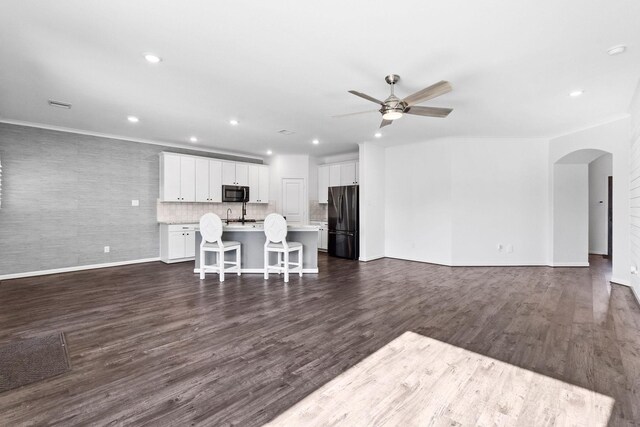 living room featuring ceiling fan, arched walkways, baseboards, recessed lighting, and dark wood finished floors