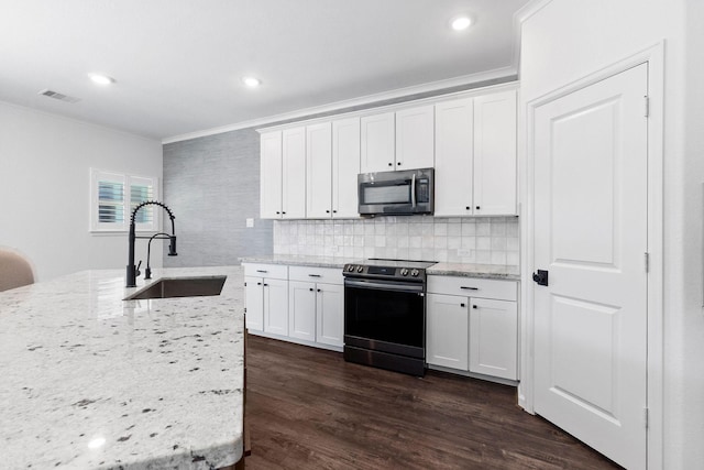 kitchen featuring stainless steel appliances, a sink, ornamental molding, white cabinetry, and backsplash