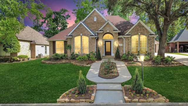 view of front of home featuring a lawn and brick siding