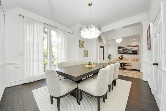 dining space featuring a decorative wall, a chandelier, ornamental molding, and dark wood-type flooring