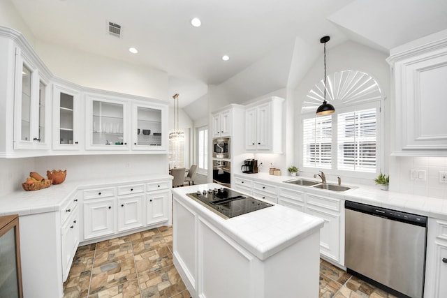 kitchen with a sink, stone finish floor, stainless steel appliances, lofted ceiling, and visible vents