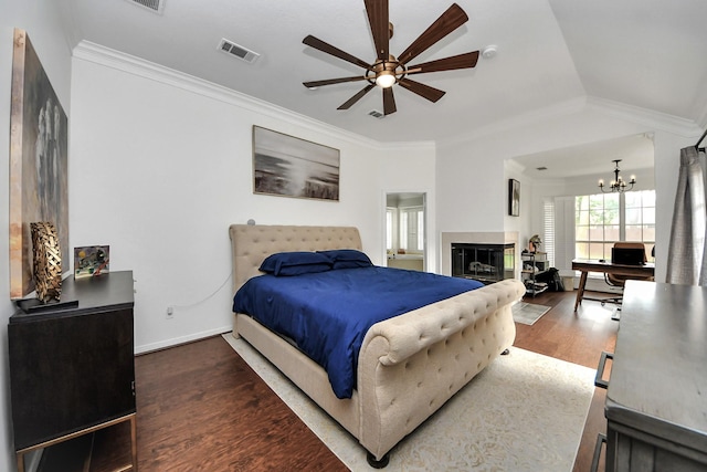 bedroom featuring crown molding, a tiled fireplace, wood finished floors, and visible vents