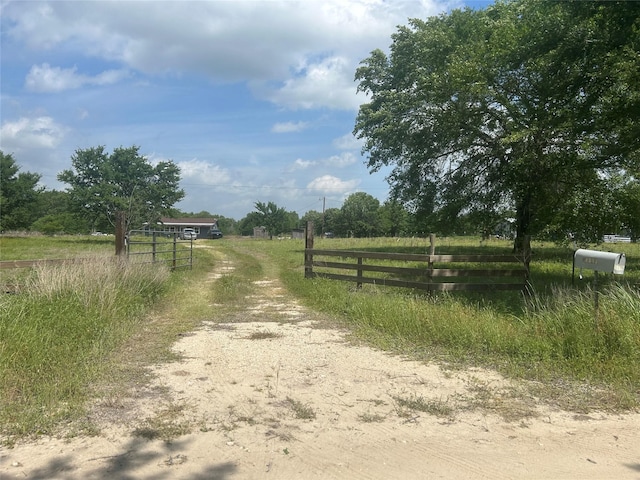view of street featuring a gated entry, a rural view, and dirt driveway