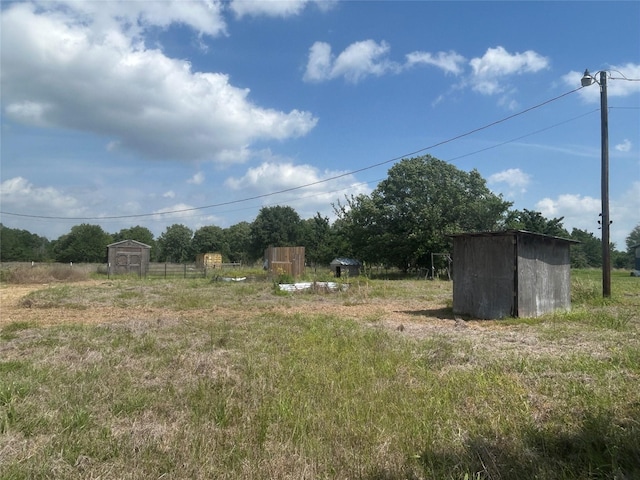 view of yard with an outdoor structure, a storage unit, and a rural view