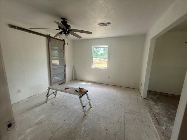 spare room with ceiling fan, a barn door, and visible vents
