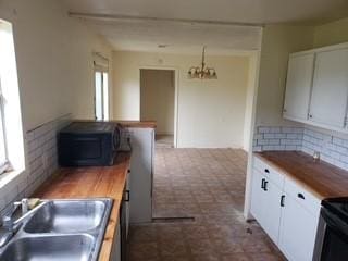 kitchen with dark floors, an inviting chandelier, a wealth of natural light, and a sink