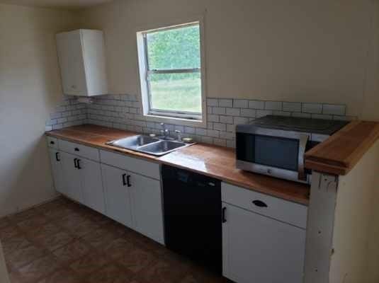 kitchen featuring water heater, backsplash, dishwasher, a sink, and stainless steel microwave