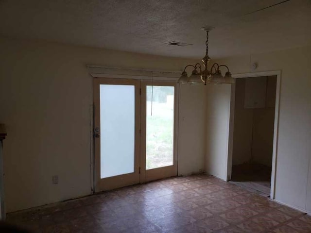 unfurnished dining area with tile patterned floors, visible vents, and a notable chandelier