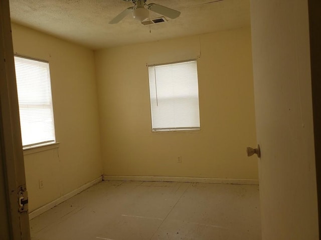 spare room with baseboards, visible vents, a textured ceiling, and ceiling fan