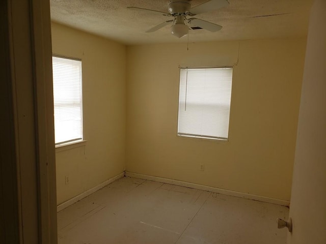 spare room featuring ceiling fan, baseboards, and a textured ceiling