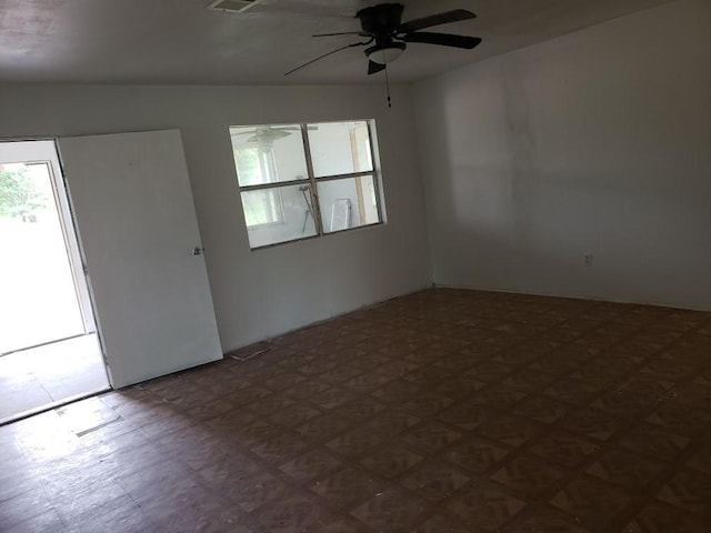 spare room featuring dark floors, visible vents, and ceiling fan