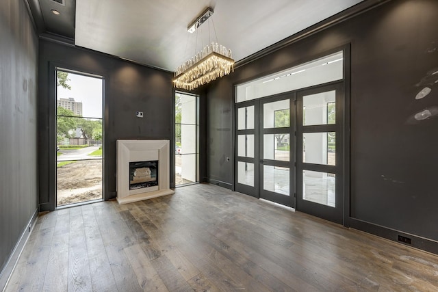 5517 Sturbridge Dr, Houston, TX 77056 - unfurnished living room featuring hardwood / wood-style flooring, a fireplace with raised hearth, a chandelier, healthy amount of natural light, and crown molding