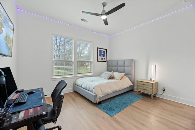 bedroom featuring ceiling fan, baseboards, visible vents, and light wood finished floors