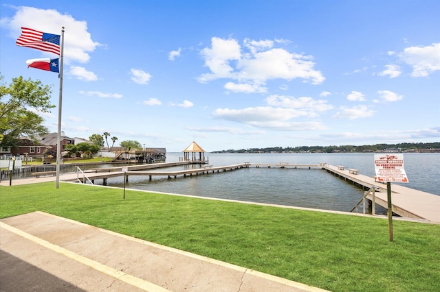 view of dock with a lawn and a water view