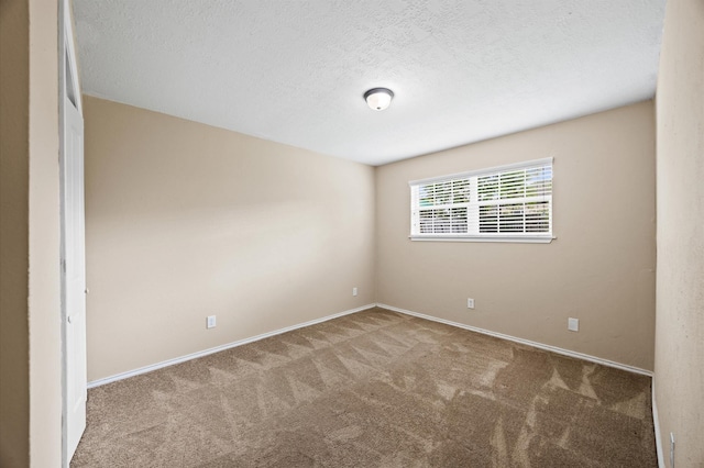 carpeted spare room featuring baseboards and a textured ceiling