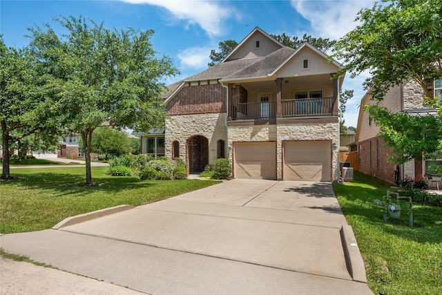 view of front of home featuring driveway, stone siding, a garage, a balcony, and a front yard