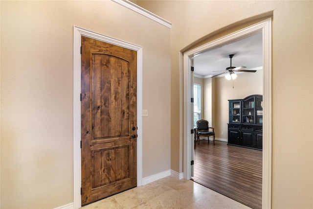 entrance foyer featuring ceiling fan, baseboards, and ornamental molding