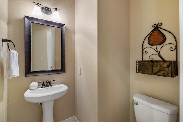 half bath featuring toilet and a sink