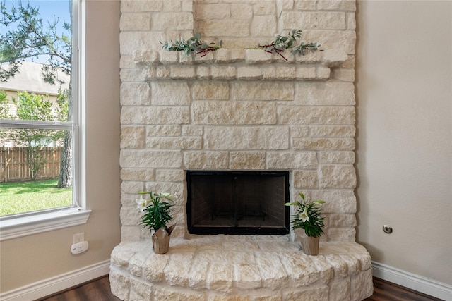 room details featuring wood finished floors, baseboards, and a stone fireplace