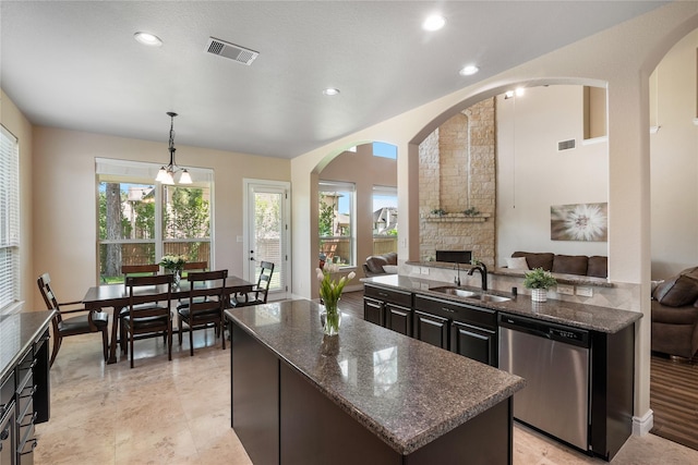 kitchen featuring stainless steel dishwasher, a sink, dark stone counters, open floor plan, and visible vents