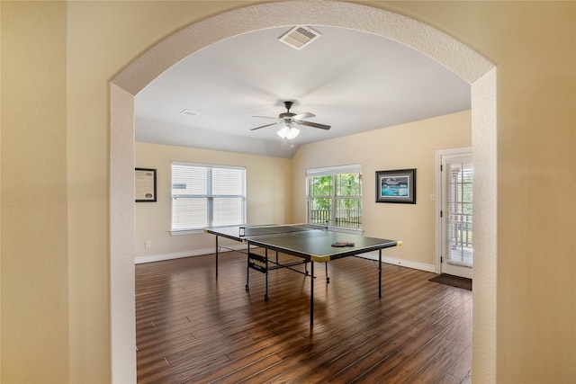game room with dark wood-style floors, arched walkways, baseboards, visible vents, and ceiling fan