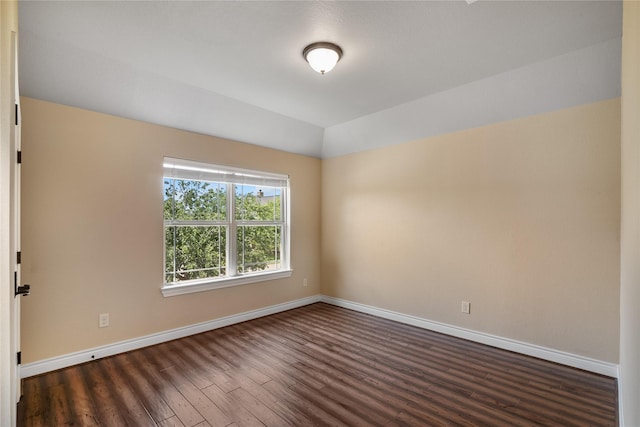 spare room with baseboards, dark wood-style flooring, and vaulted ceiling