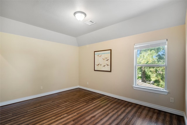 unfurnished room with lofted ceiling, baseboards, visible vents, and dark wood finished floors