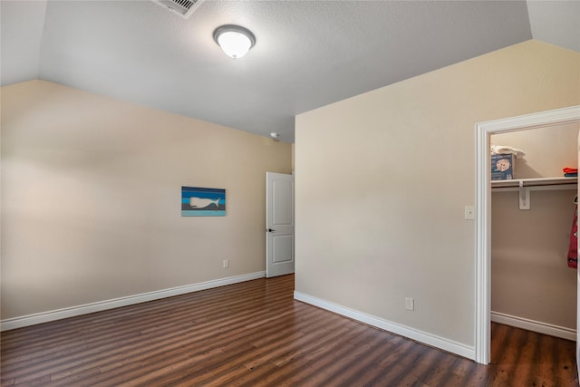 unfurnished bedroom featuring baseboards, vaulted ceiling, wood finished floors, and a closet