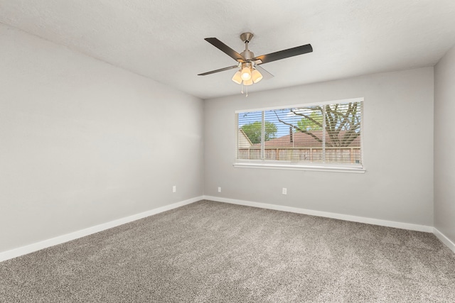 carpeted spare room with a ceiling fan and baseboards