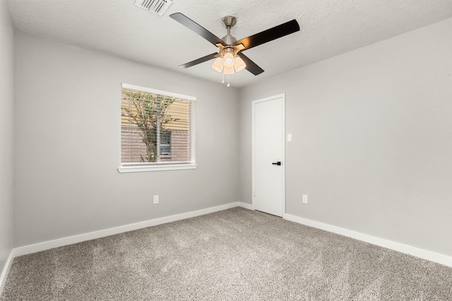 empty room with carpet flooring, a textured ceiling, a ceiling fan, baseboards, and visible vents