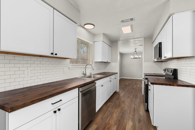 kitchen featuring a sink, wood counters, stainless steel appliances, backsplash, and visible vents