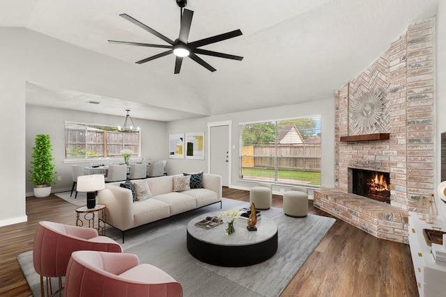 living area with a brick fireplace, a wealth of natural light, wood finished floors, and lofted ceiling