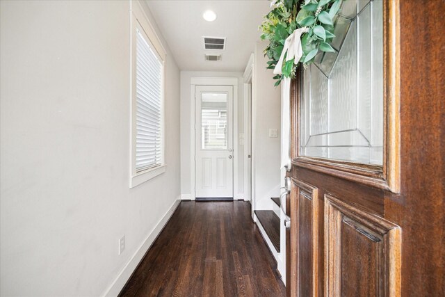 corridor with baseboards, visible vents, and wood finished floors
