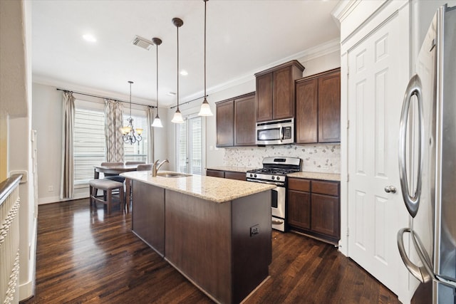 kitchen with an island with sink, appliances with stainless steel finishes, ornamental molding, dark brown cabinets, and visible vents