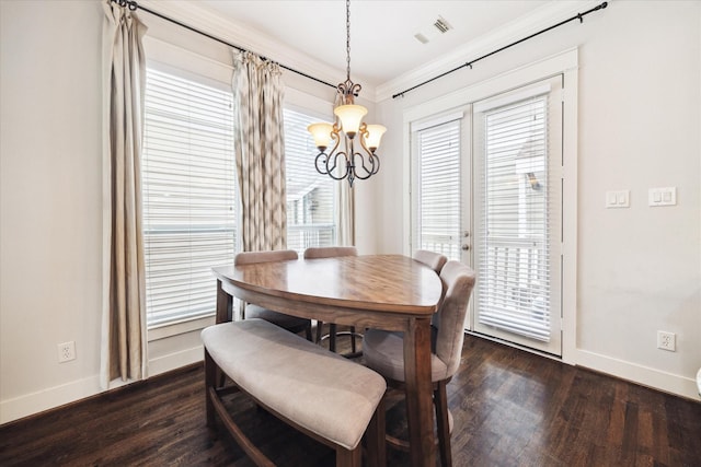 dining space featuring a notable chandelier, dark wood-type flooring, crown molding, visible vents, and baseboards
