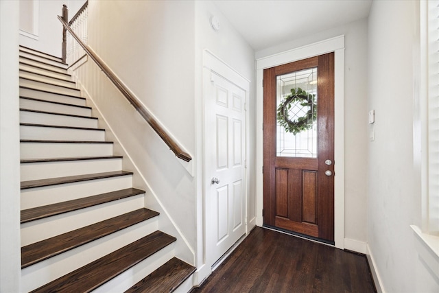 entryway with dark wood-style flooring, baseboards, and stairs