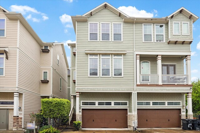 multi unit property featuring a garage, driveway, and stone siding