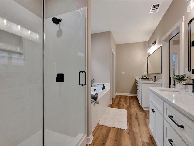 282 Lancewood Cir, Hudson, TX 75904 - bathroom with two vanities, a sink, a stall shower, visible vents, and wood finished floors