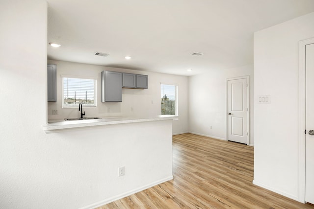 kitchen with a sink, gray cabinets, a wealth of natural light, baseboards, and visible vents