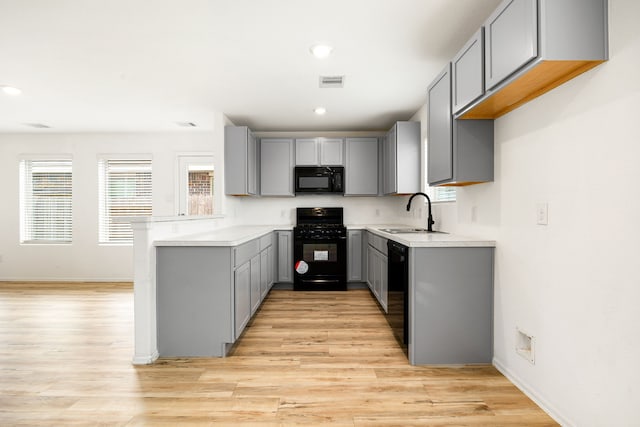 kitchen with a sink, plenty of natural light, black appliances, gray cabinetry, and visible vents