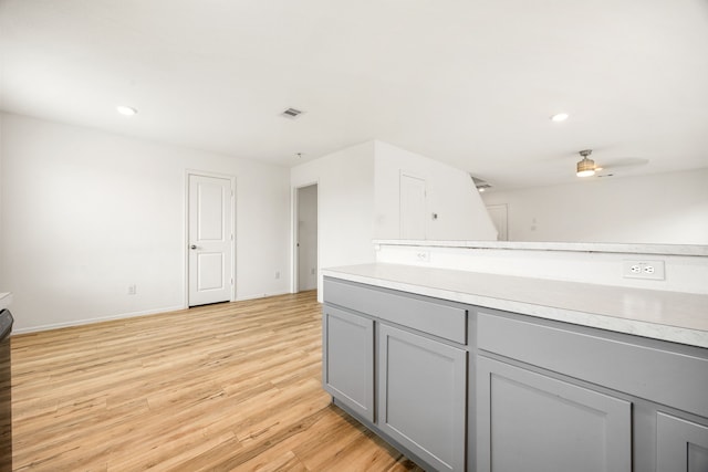kitchen featuring a ceiling fan, light wood-style floors, light countertops, baseboards, and gray cabinetry