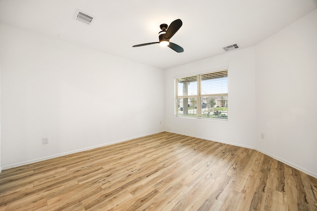 spare room with baseboards, a ceiling fan, light wood finished floors, and visible vents