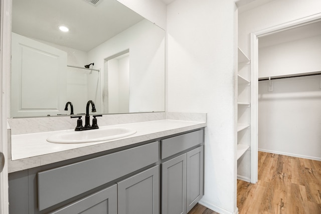 full bathroom with a shower, wood finished floors, vanity, and a walk in closet