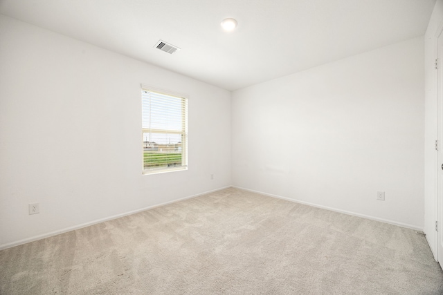 spare room featuring baseboards, visible vents, and light colored carpet