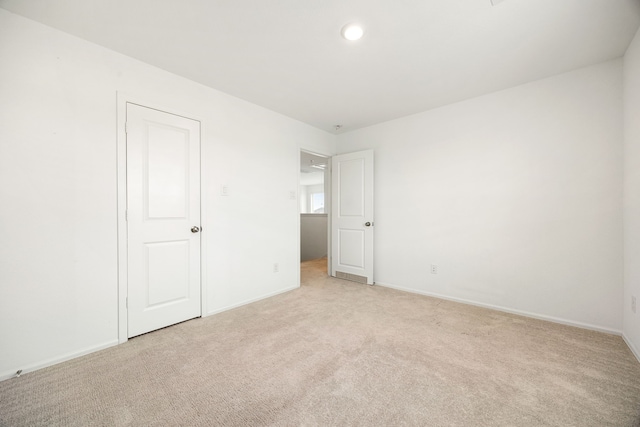 unfurnished bedroom featuring light colored carpet and baseboards