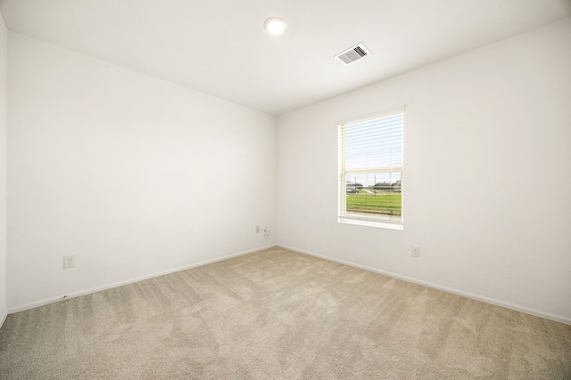 spare room with light carpet, baseboards, and visible vents