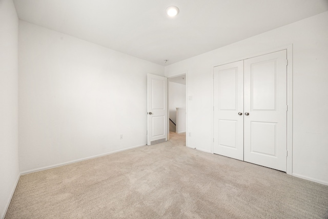 unfurnished bedroom with baseboards, a closet, and light colored carpet
