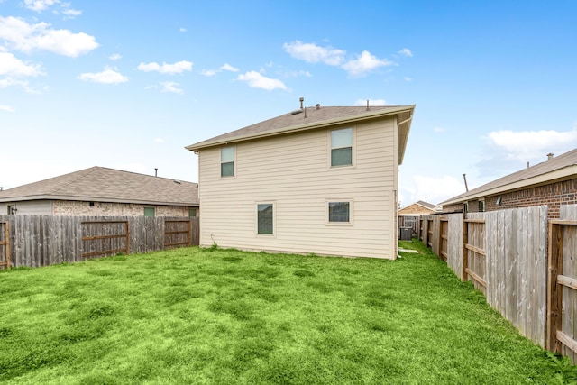 rear view of property with a fenced backyard and a yard