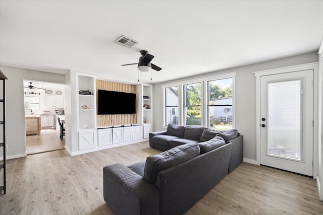 living room featuring visible vents, built in features, a ceiling fan, and wood finished floors